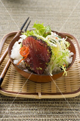 Raw tuna fillet with poppy seeds, rice and salad