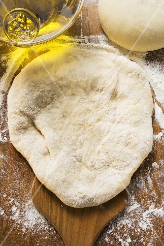 Uncooked dough, rolled out and in a ball, olive oil