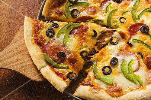 Pizza with cheese, salami, peppers and olives, pieces cut
