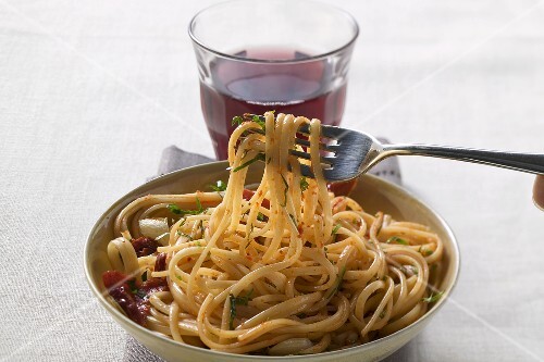 Spaghetti with dried peppers, glass of red wine