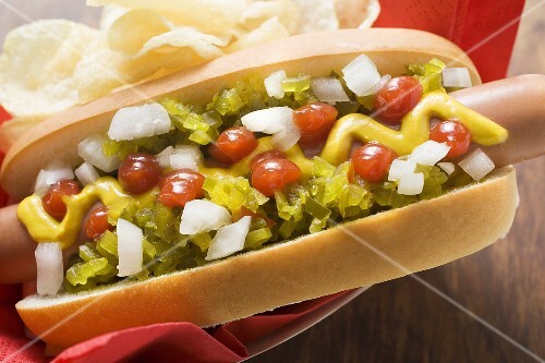 Hot dog with relish, mustard, ketchup, onions and crisps
