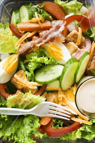 Salad leaves with egg, cheese, bacon and dressing to take away