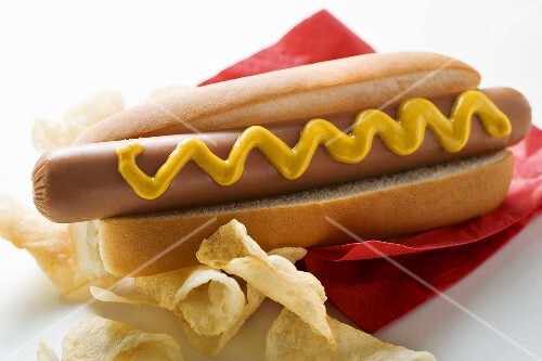 Hot dog with mustard and potato crisps on red napkin