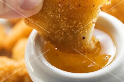 Dipping a chicken nugget in apricot sauce