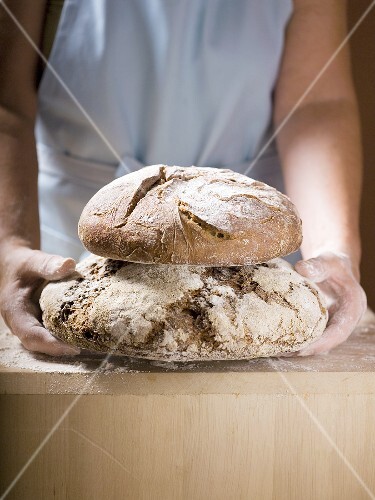 Woman holding two loaves of Bauernbrot (German farmhouse bread)