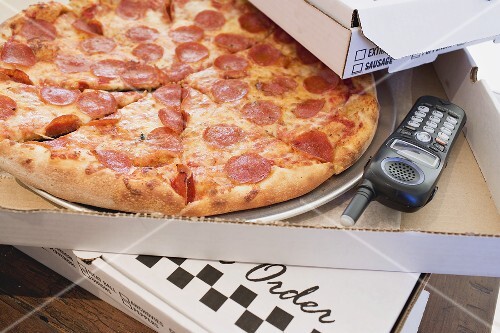 Pepperoni pizza in pizza box, telephone beside it