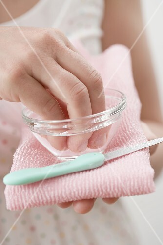 Young woman soaking her finger tips in a small dish