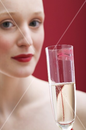 Young woman holding glass of sparkling wine with lipstick mark