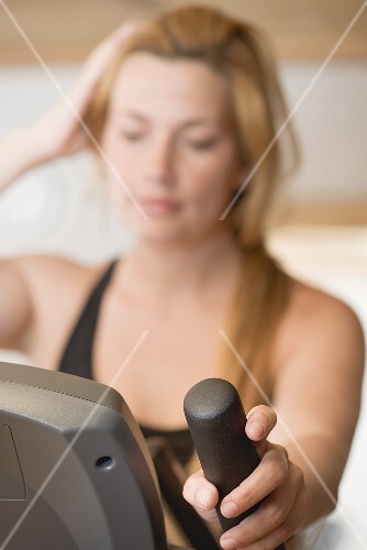 Blonde Frau trainiert am Crosstrainer