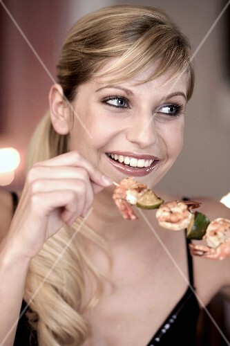 Young woman eating a shrimp kebab