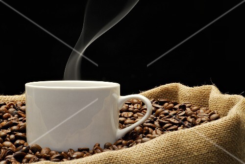 A cup of coffee on a jute sack full of coffee beans
