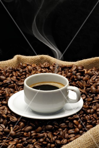 A cup of coffee on a jute sack full of coffee beans