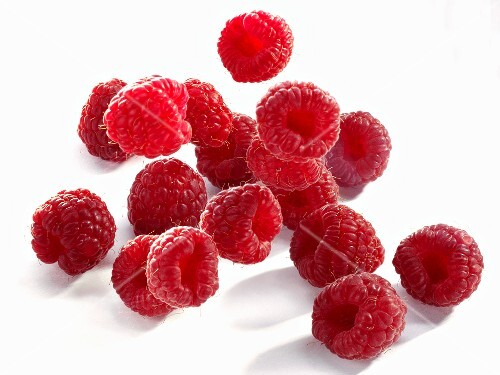 Raspberries falling onto a light surface