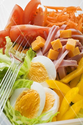 Mixed salad with ham and egg in plastic container