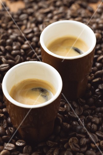 Zwei Espresso stehen auf Kaffeebohnen