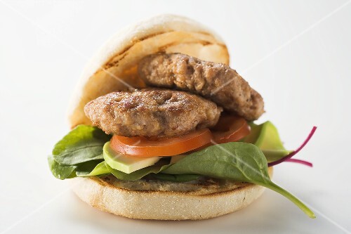 Meat patties with spinach and avocado in hamburger roll