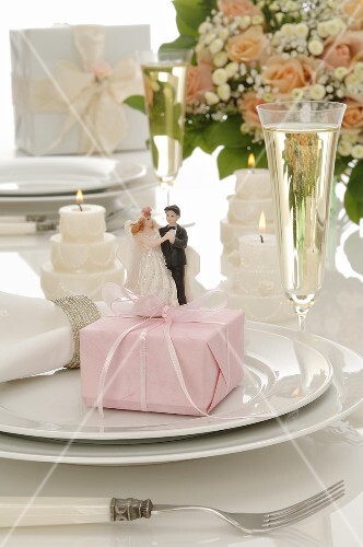 Wedding place-setting: gift, bride & groom figures, glass ofwine