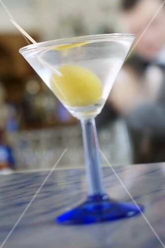Drink with olive on a bar counter