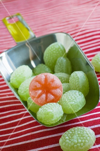Green sweets and one red sweet in a scoop