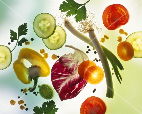 Vegetables, herbs, salad leaves & seasonings on a sheet of glass