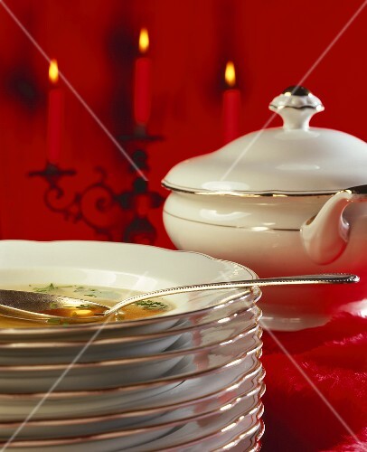 Stack of plates with soup in top plate, soup tureen