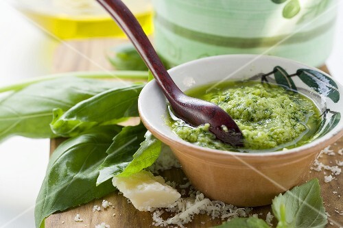 Pesto with olive oil in small bowl, basil, Parmesan
