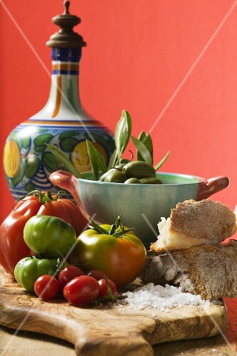 Fresh tomatoes, olives, bread, salt and ceramic jug