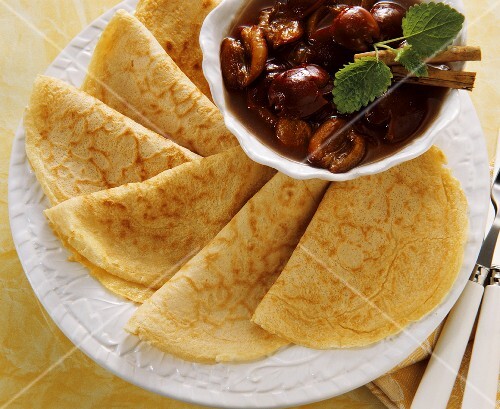 Several folded crepes with a bowl of cherries