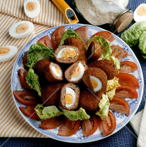 Hard-boiled eggs in mince casing on lettuce leaves