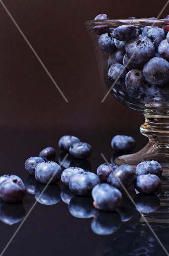 Blueberries in and beside a glass bowl