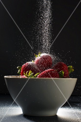 Sugar Pouring Over a Bowl of Strawberries