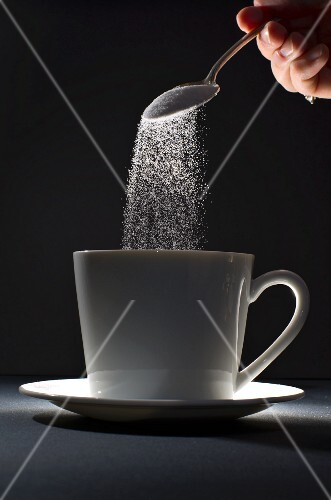 Pouring Spoonful of Sugar into a Coffee Mug