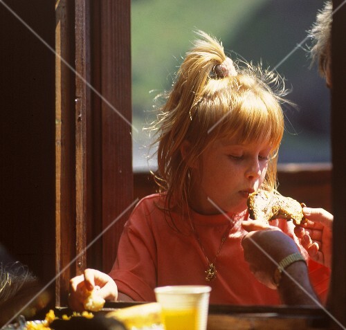 Blond girl biting into a chicken leg