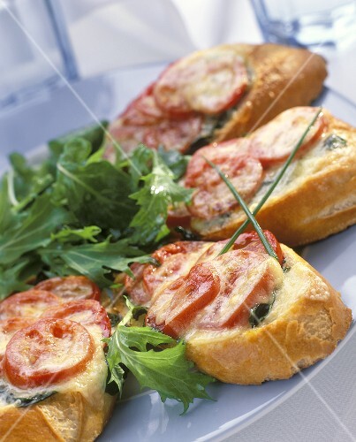Toasted baguette slices with tomatoes & cheese on plate