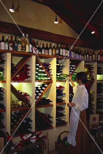 Verkauferin in einer Weinhandlung sortiert Weinflaschen