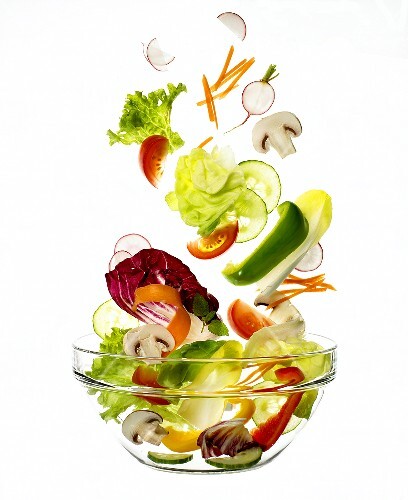 Salatzutaten fallen in eine Schüssel