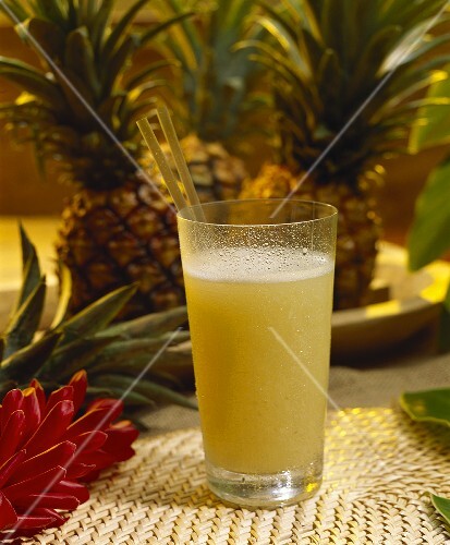 Freshly squeezed pineapple juice in glass with two straws