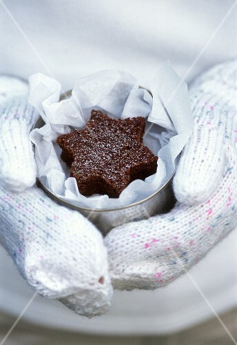 Hand hält Dose mit sternförmigem Schokokuchen