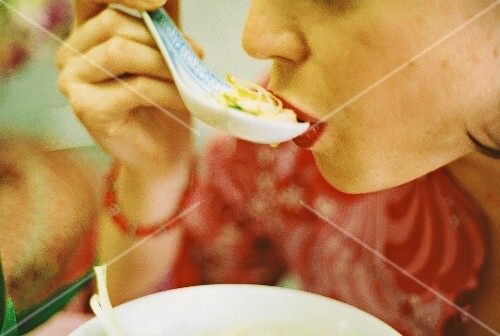Woman eating Asian chicken & vegetable soup (surreal photo, 2)