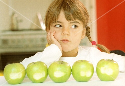 Small girl in front of green apple with bite taken