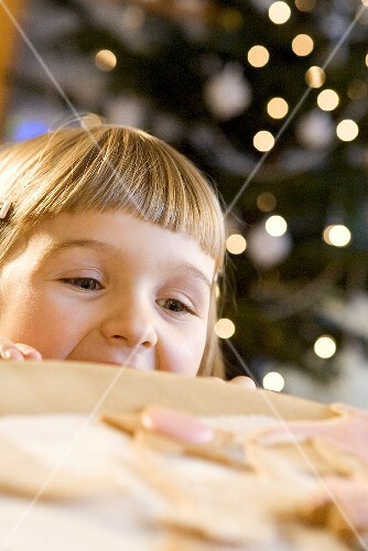 Small girl looking at biscuits over edge of table