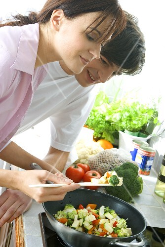 Young couple frying vegetables in wok (2)
