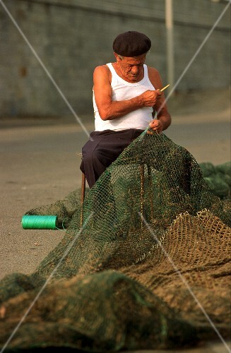 Fisherman mending fishing net in San Remo, N. Italy
