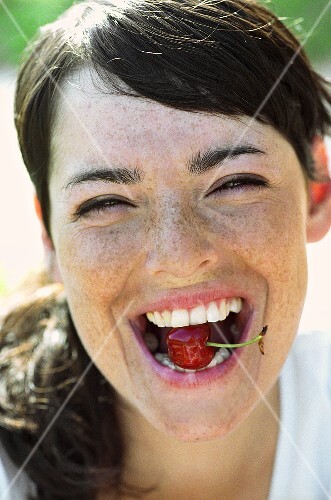 Portrait of a young woman with a cherry in her mouth