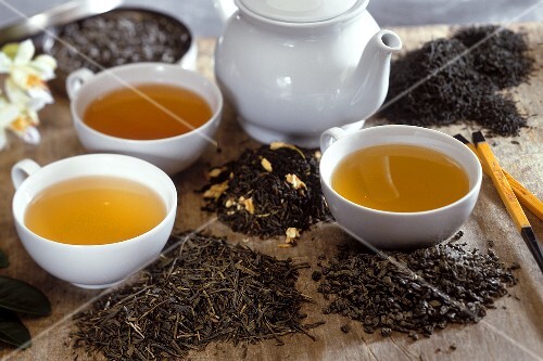Various green teas in white cups with tea leaves