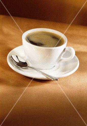 Espresso in a white cup with a spoon on the saucer