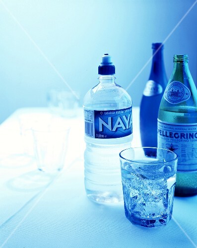 Mineral water in glass and various bottles