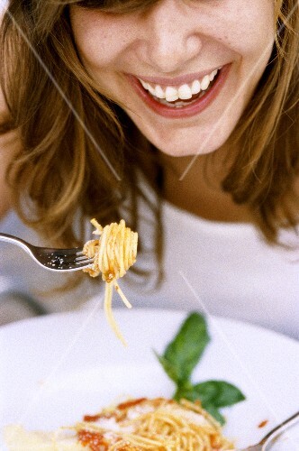 Woman eating spaghetti with tomato sauce