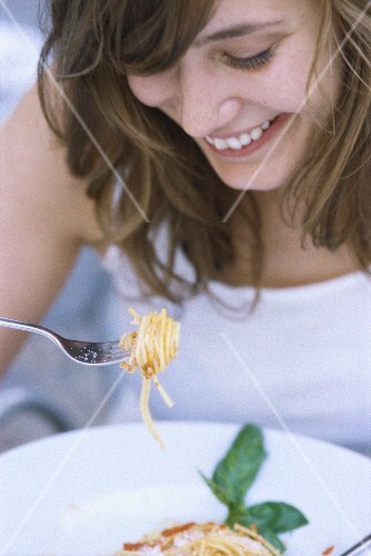 Woman eating spaghetti with tomato sauce