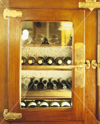 Several wine bottles in wood-panelled drinks cabinet